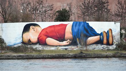 Ein Graffito zeigt den ertrunkenen zweijährigen Alan Kurdi auf der Osthafenmole in Frankfurt am Main.