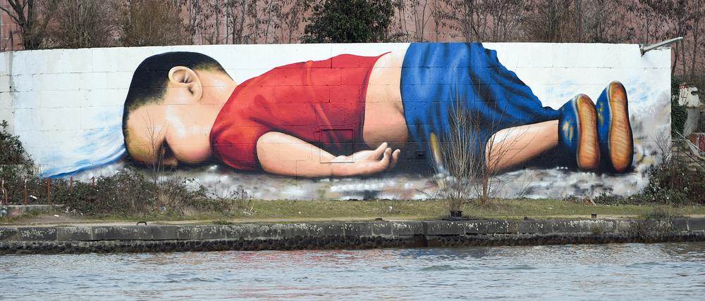 Ein Graffito zeigt den ertrunkenen zweijährigen Alan Kurdi auf der Osthafenmole in Frankfurt am Main.