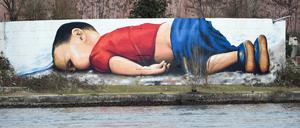 Ein Graffito zeigt den ertrunkenen zweijährigen Alan Kurdi auf der Osthafenmole in Frankfurt am Main.