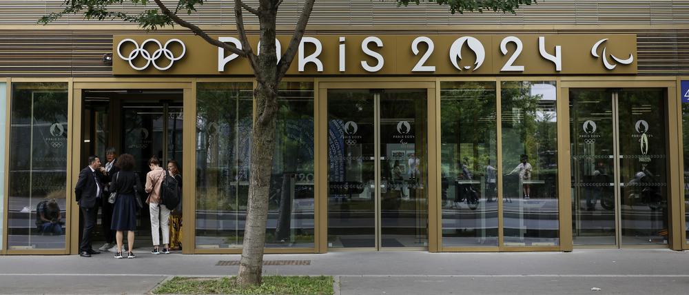 20.06.2023, Frankreich, Saint-Denis: Menschen warten vor dem Hauptsitz der Pariser Olympia-Organisatoren. Im Rahmen von Untersuchungen der französischen Finanzstaatsanwaltschaft ist der Sitz des Organisationskomitees für die Olympischen Spiele 2024 durchsucht worden. Foto: Thomas Padilla/AP/dpa +++ dpa-Bildfunk +++