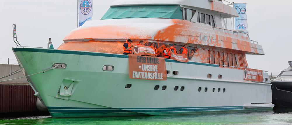 Teilnehmer einer Protestaktion stehen mit Transparenten auf einer Yacht im Hafen von Neustadt.