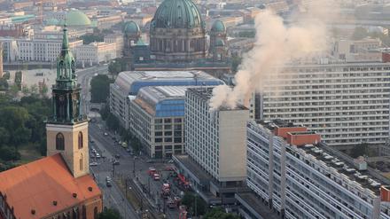 Rauch steigt aus einem Hochhaus, im Hintergrund der Berliner Dom. In einem Hochhaus in der Nähe des Berliner Alexanderplatzes ist am Dienstagabend ein Feuer ausgebrochen.