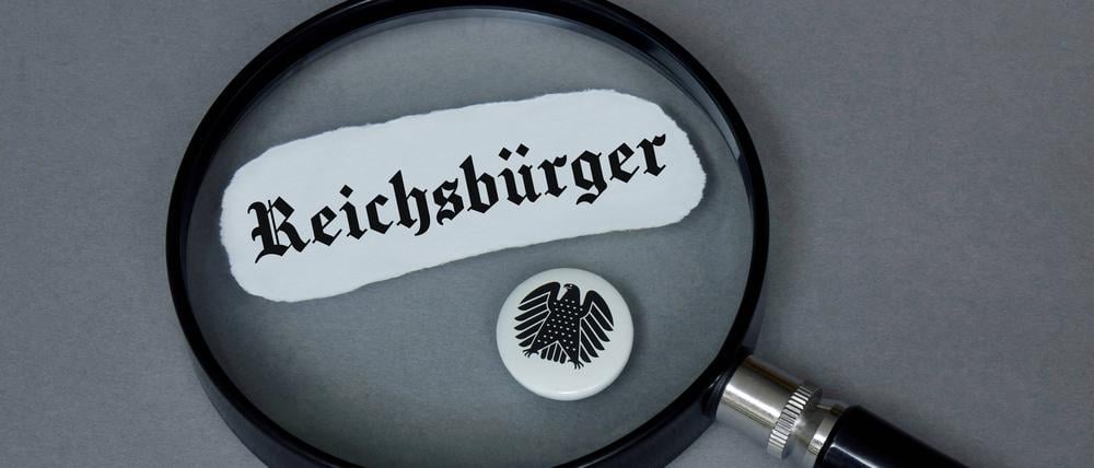 Lupe mit Reichsbürger und Button mit Bundesadler, Symbolbild