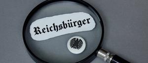Lupe mit Reichsbürger und Button mit Bundesadler, Symbolbild