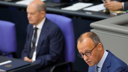 Bundeskanzler Olaf Scholz hört zu, als Friedrich Merz, Vorsitzender der CDU eine Rede vor den Abgeordneten des Bundestages in Berlin hält.