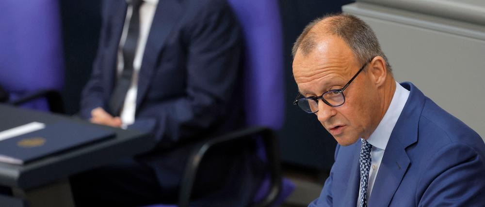 Bundeskanzler Olaf Scholz hört zu, als Friedrich Merz, Vorsitzender der CDU eine Rede vor den Abgeordneten des Bundestages in Berlin hält.