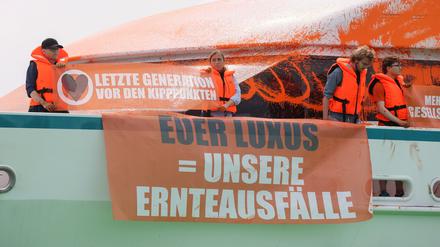 Teilnehmer einer Protestaktion stehen mit Transparenten auf einer Yacht im Hafen von Neustadt. 