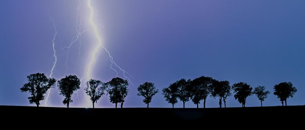 Ein Blitz eines Gewitters erhellt den Nachthimmel über der Landschaft im Osten des Landes Brandenburg.
