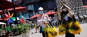 Menschen schützen sich vor der Sonne, während sie inmitten einer Hitzewelle in Peking unterwegs sind (Symbolbild).