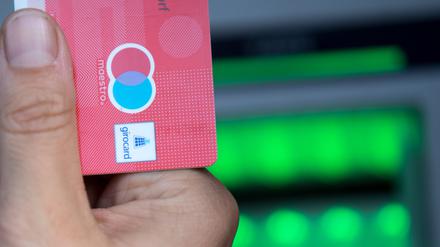 Eine Bankkundin hebt mit ihrer Girokarte, mit rot-blauem Maestro-Logo, Bargeld von einem Geldautomaten ab. Das Logo soll von den Girokarten verschwinden.
