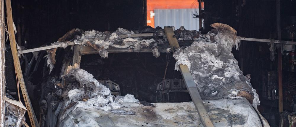 24.06.2023, Mecklenburg-Vorpommern, Jarmen: Ein ausgebranntes Auto steht in einer Garage an der Brandruine eines Einfamilienhaus in Jarmen.