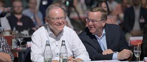 Boris Pistorius (r; SPD), Bundesverteidigungsminister, und Stephan Weil (SPD), Ministerpräsident von Niedersachsen, sitzen während des Parteitags in einer Halle und unterhalten sich.