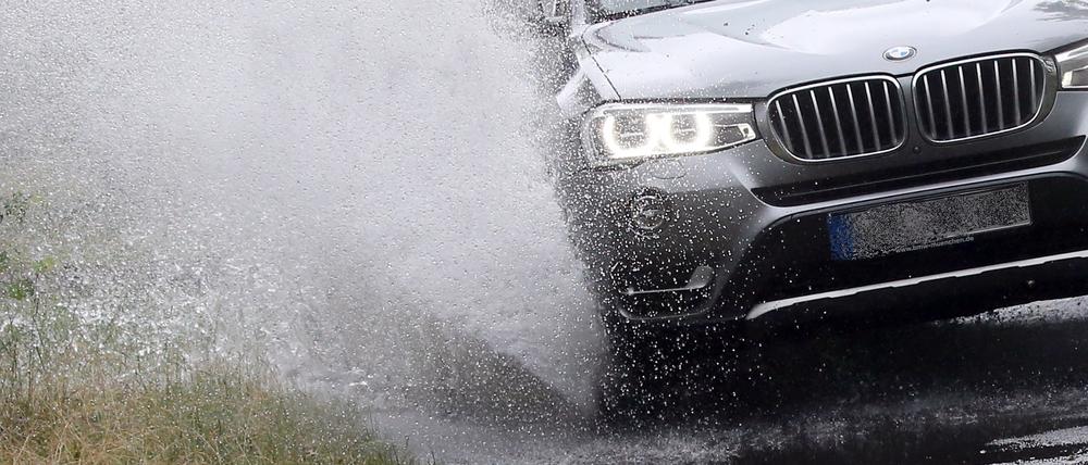 Ein Auto fährt durch eine Regenpfütze.