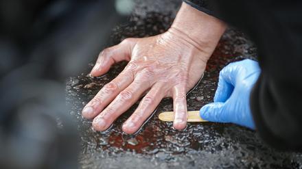 Ein Polizeibeamter löst die Hand eines Klimaaktivisten von der Straße,