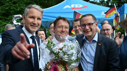 Björn Höcke  (l) , Vorsitzender der AfD Thüringen und Tino Chrupalla, AfD-Bundesvorsitzender (r) gratulieren dem Wahlsieger des Thüringer Kreis Sonneberg, Robert Sesselmann (AfD, M) im Garten eines Restaurant.