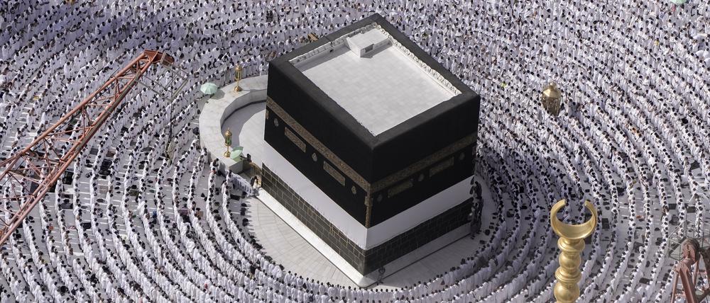 Muslimische Pilger stehen betend um die Kaaba herum.