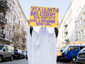 Eine Aktivistin im Gespensterkostüm hält ein Protestschild nahe dem Organisationsbüro des Volksbegehrens «Deutsche Wohnen & Co. enteignen» in die Kamera. Auf dem Schild ist zu lesen «Spekulanten eure Zeit ist im, das Gespenst der Enteignung geht um!».