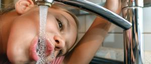 Ein Mädchen trinkt Leitungswasser aus einem Wasserhahn. (Symbolbild)