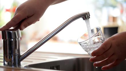 Leitungswasser fließt sprudelnd aus einem Wasserhahn in ein Glas.