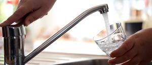 Leitungswasser fließt sprudelnd aus einem Wasserhahn in ein Glas.