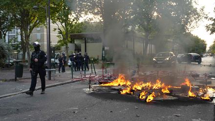 Polizisten in Einsatzkleidung stehen neben einem Feuer, das nach einer Demonstration in Nanterre, westlich von Paris, am 27. Juni 2023 auf der Straße brennt.