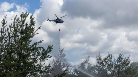 Ein Puma-Hubschrauber der Bundespolizei fliegt über dem Brand und wirft Löschwasser auf den Boden. Seit zwei Tagen brennt ein Walstück in der Gohrischheide im Landkreis Meißen. 