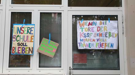 Mit selbst gebastelten Schildern protestieren Schüler und Eltern vor dem Schulgebäude.