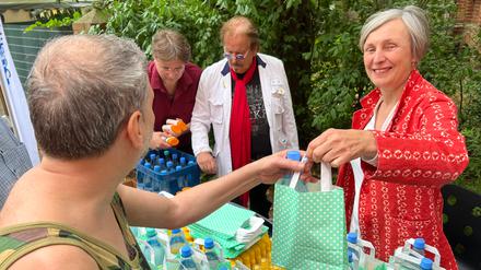 Ursula Schoen gibt bei der Aktion Warmes Essen gemeinsam mit Frank Zander Tüten mit Sonnencreme und Wasser aus.