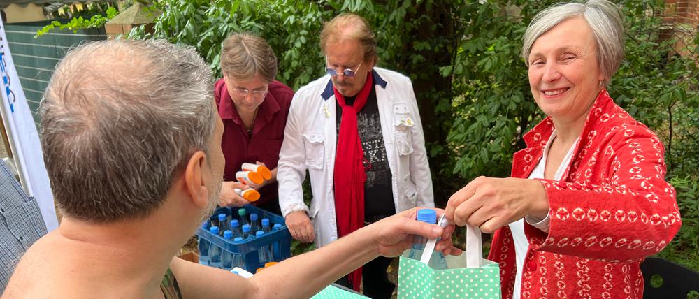 Ursula Schoen gibt bei der Aktion Warmes Essen gemeinsam mit Frank Zander Tüten mit Sonnencreme und Wasser aus.