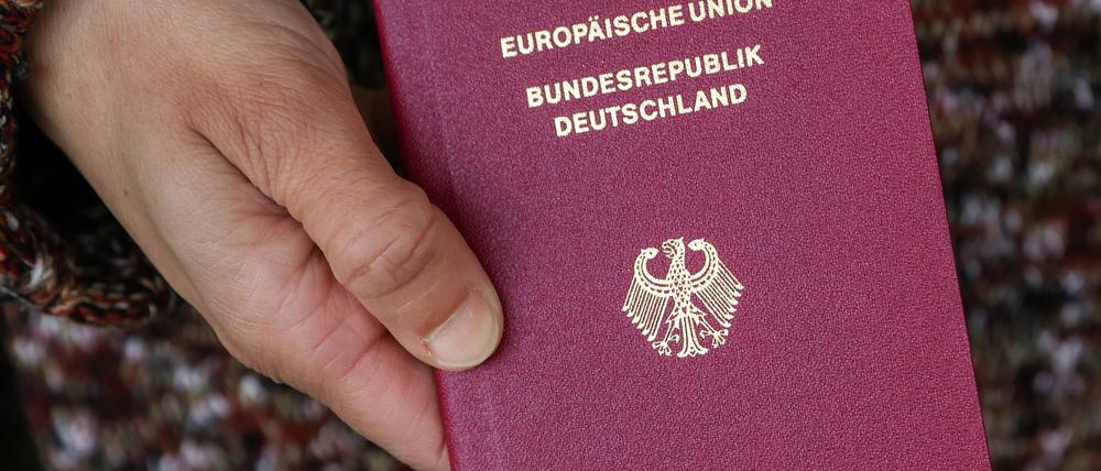 Eine Frau mit Migrationswurzeln hält ihren deutschen Reisepass in den Händen.