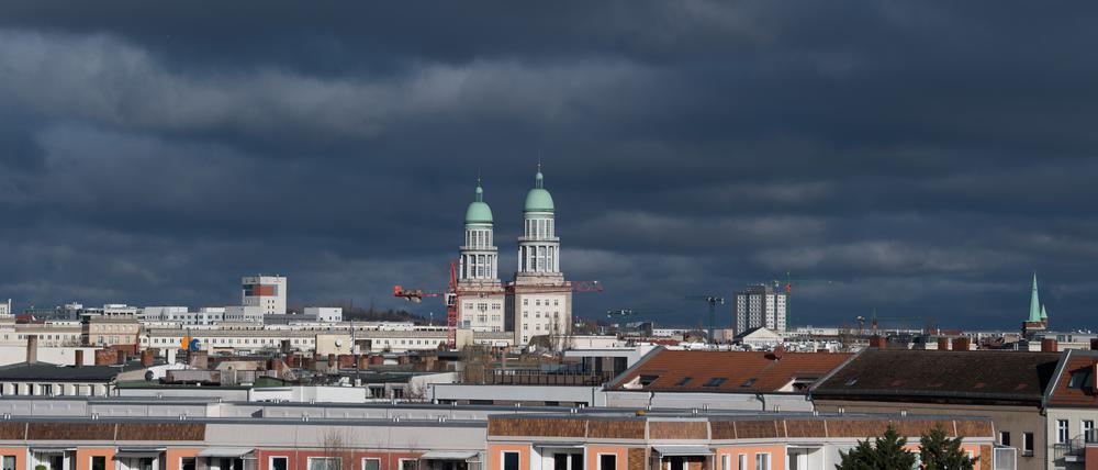 Die beiden Wohntürme am Frankfurter Tor sind über den Dächern von Wohn- und Geschäftshäusern im Stadtteil Friedrichshain vor dunklen Wolken zu sehen.