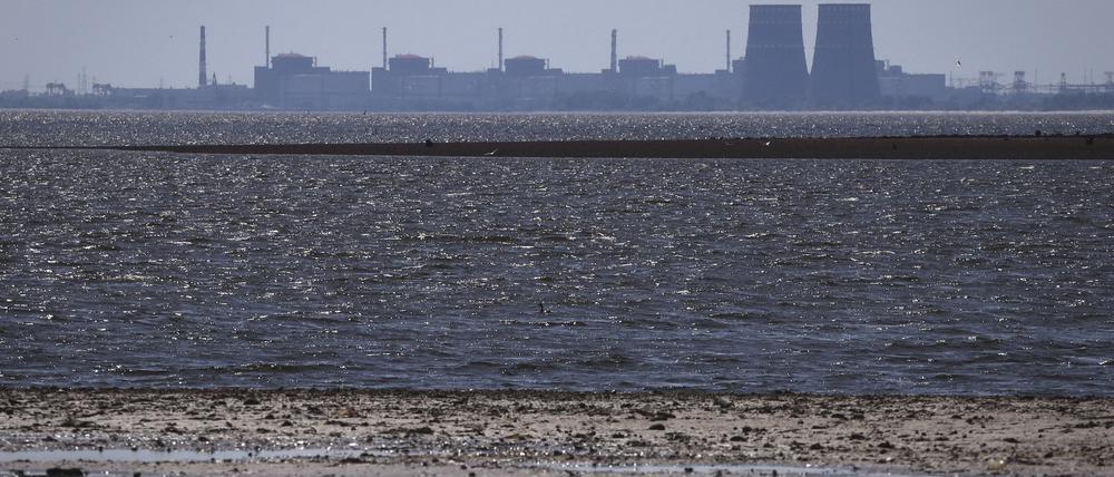 ARCHIV - 09.06.2023, Ukraine, Energodar: Das Kernkraftwerk Saporischschja ist im Hintergrund des flachen Kachowka-Stausees nach der Zerstörung des Kachowka-Staudamms zu sehen.