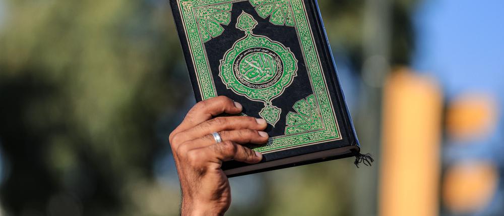 Ein Mann hält ein Exemplar des Koran während eines Protests. Nach der Verbrennung eines Korans in Schweden haben im Irak Hunderte Menschen demonstriert.