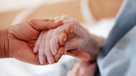 Eine Betreuerin hält die Hand einer älteren Frau.
