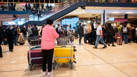 Passagiere am Flughafen BER warten in der Flughafenhalle auf ihre Abfertigung.