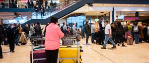 Passagiere am Flughafen BER warten in der Flughafenhalle auf ihre Abfertigung.