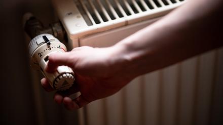 Eine Person benutzt einen alten Heizkörper in einer Berliner Altbauwohnung. 