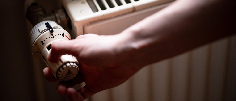 Eine Person benutzt einen alten Heizkörper in einer Berliner Altbauwohnung.