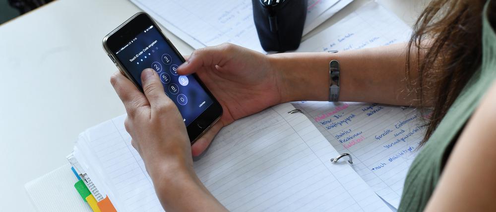 Eine Schülerin entsperrt im Unterricht in einer Berliner Schule ihr Smartphone.