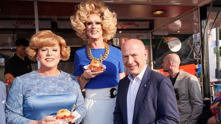 Kai Wegner (CDU), Regierender Bürgermeister Berlin, steht mit Margot Schlönzke (l) und Jurassica Parka beim Berliner Hoffest vor dem Roten Rathaus beim Curry36.