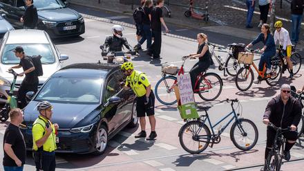 Ein Fahrradpolizist stoppt einen Autofahrer am Rande der Demo. 