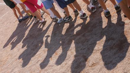 Kinder einer Grundschule stehen bei einer Veranstaltung im Rahmen der Bundesjugendspiele auf einem Sportplatz.