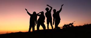 4 friends are stylish on the hill with a beautiful view of the afternoon sky