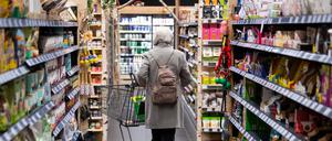 Eine Frau geht mit ihrem Einkaufswagen durch einen Supermarkt