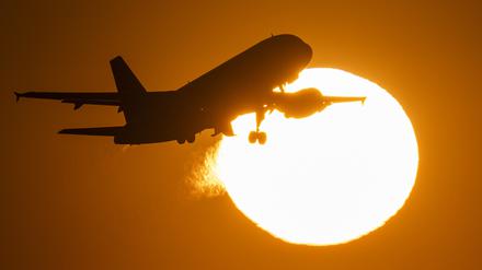 Eine Passagiermaschine hebt vor der untergehenden Sonne ab. 