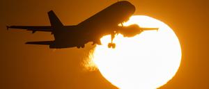 Eine Passagiermaschine hebt vor der untergehenden Sonne ab.