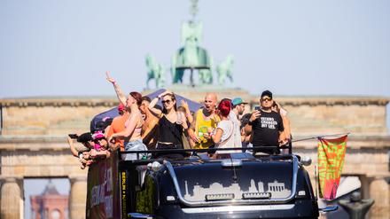 Menschen feiern bei der Technoparade «Rave the Planet» auf einem Wagen vor der Quadriga des Brandenburger Tors.
