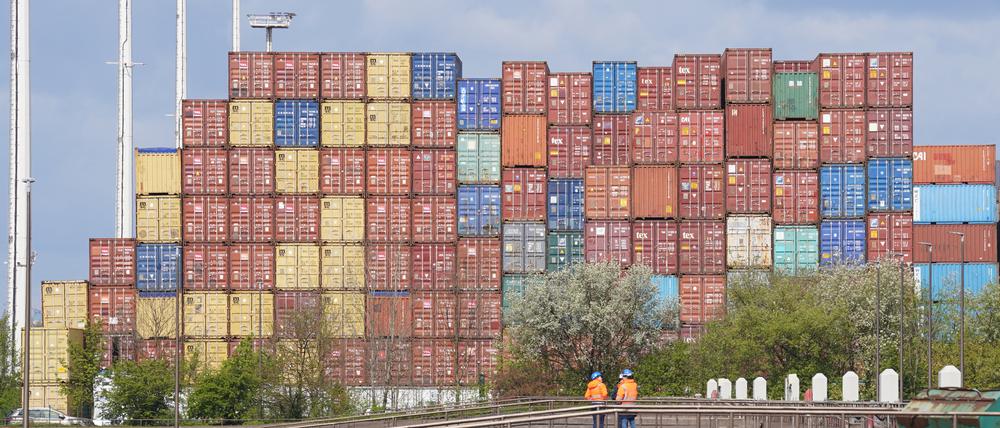 Arbeiter stehen vor Überseecontainer auf einem Terminal im Hafen. Vertreter der EU und Neuseelands haben ein gemeinsames Freihandelsabkommen unterschrieben.