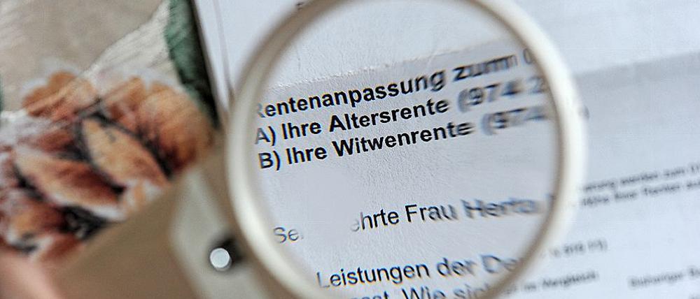 Ein Rentenbescheid wird mit einer Leselupe gelesen (Symbolbild). 