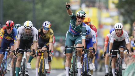 Jasper Philipsen (M) aus Belgien vom Team Alpecin-Deceuninck zeigt vier Finger, während er vor dem Drittplatzierten Phil Bauhaus (2.v.l.) aus Deutschland vom Team Bahrain Victorious als Etappensieger über die Ziellinie fährt. 